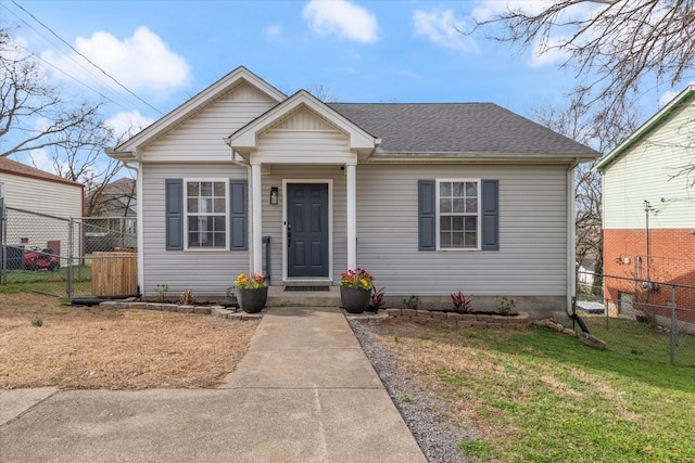 bungalow-style house with roof with shingles, a front lawn, and fence