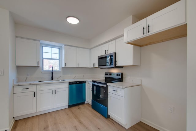 kitchen with light countertops, white cabinets, appliances with stainless steel finishes, and a sink