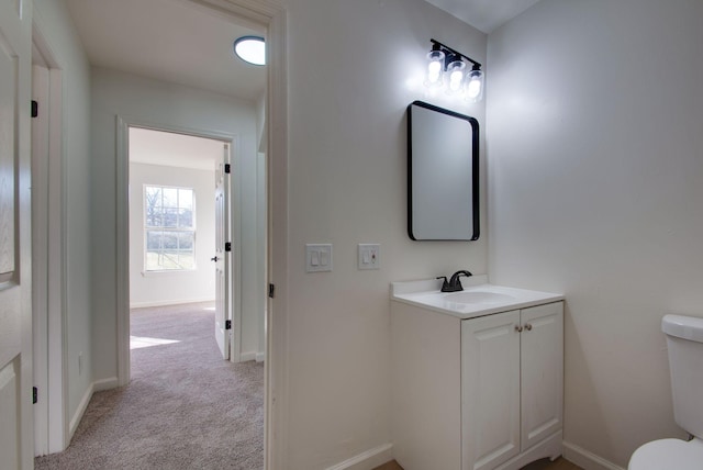 half bath featuring baseboards, toilet, and vanity