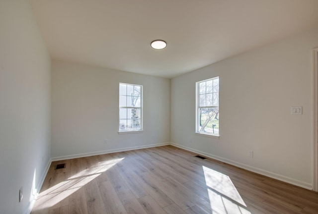 empty room featuring visible vents, baseboards, and wood finished floors