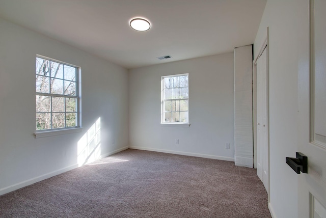 empty room with visible vents, baseboards, and carpet