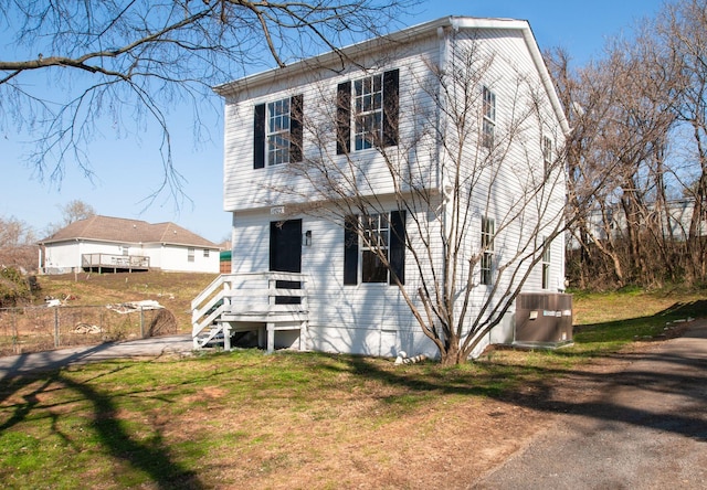 view of front facade featuring cooling unit, a front yard, and fence