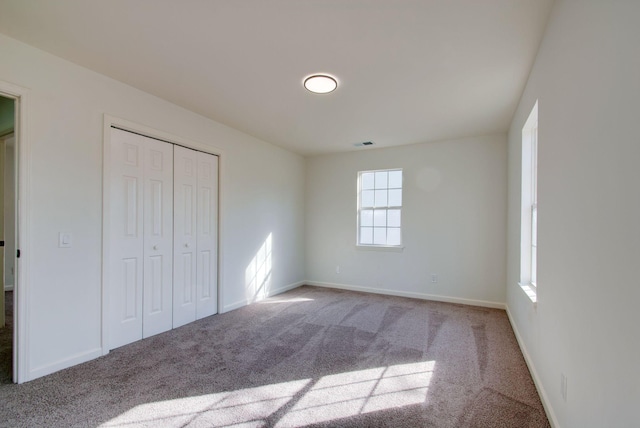 unfurnished bedroom featuring a closet, visible vents, baseboards, and carpet