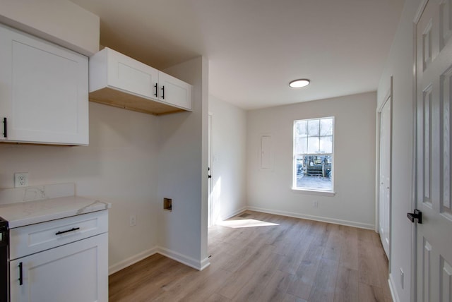 kitchen with light stone counters, light wood-style flooring, baseboards, and white cabinets