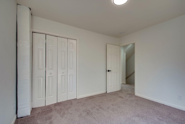 unfurnished bedroom with carpet, a closet, and baseboards