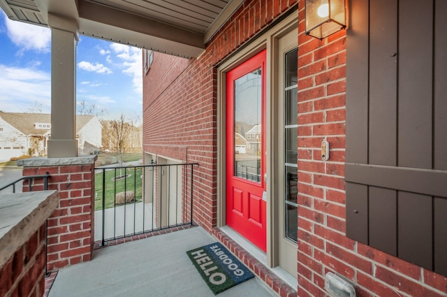 view of exterior entry featuring brick siding and a balcony