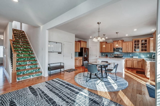 dining room featuring light wood-style flooring, recessed lighting, stairway, an inviting chandelier, and baseboards