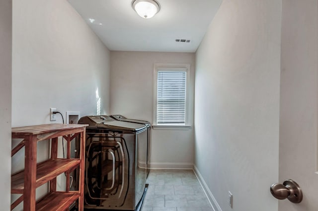 laundry room with visible vents, baseboards, light tile patterned floors, laundry area, and separate washer and dryer