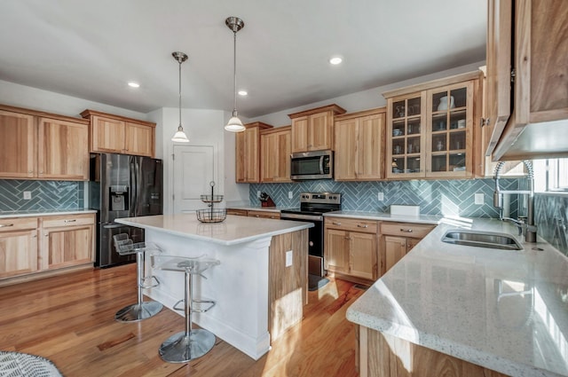 kitchen featuring light wood-style flooring, a sink, a kitchen island, stainless steel appliances, and a breakfast bar area