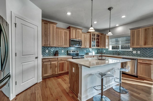 kitchen featuring light wood-type flooring, a sink, a kitchen breakfast bar, a center island, and appliances with stainless steel finishes