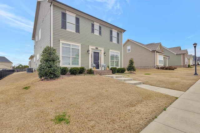 colonial home with central air condition unit, a front yard, and fence