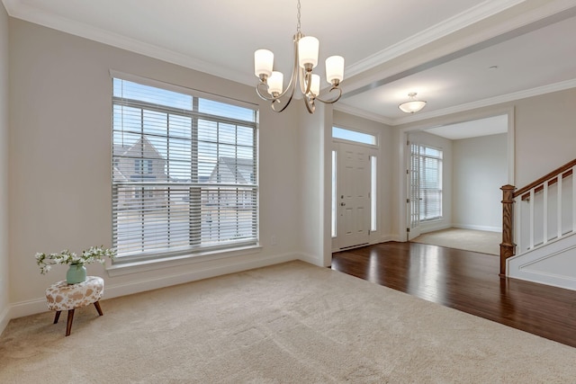 carpeted entryway with crown molding, baseboards, a chandelier, stairway, and wood finished floors