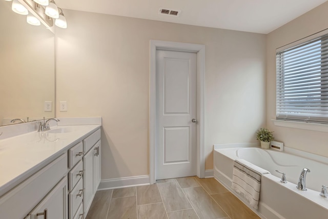 full bathroom featuring visible vents, baseboards, a garden tub, and vanity