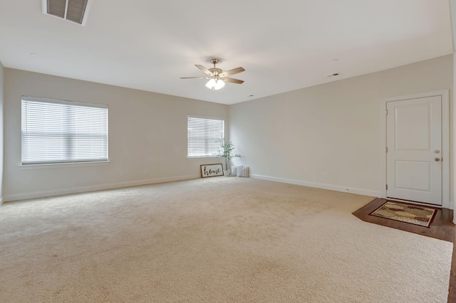 unfurnished room featuring visible vents, baseboards, light colored carpet, and a ceiling fan