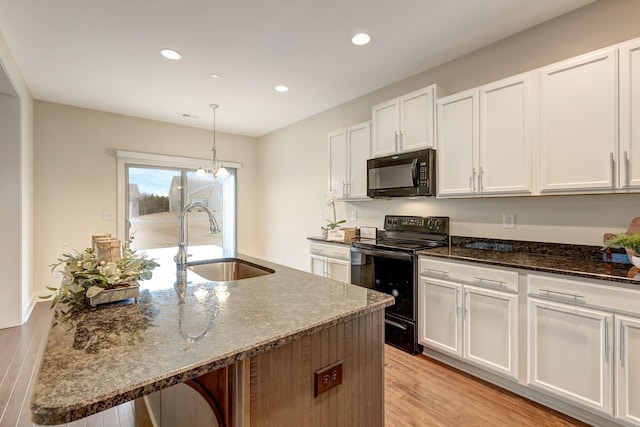 kitchen with dark stone countertops, light wood-style flooring, recessed lighting, a sink, and black appliances