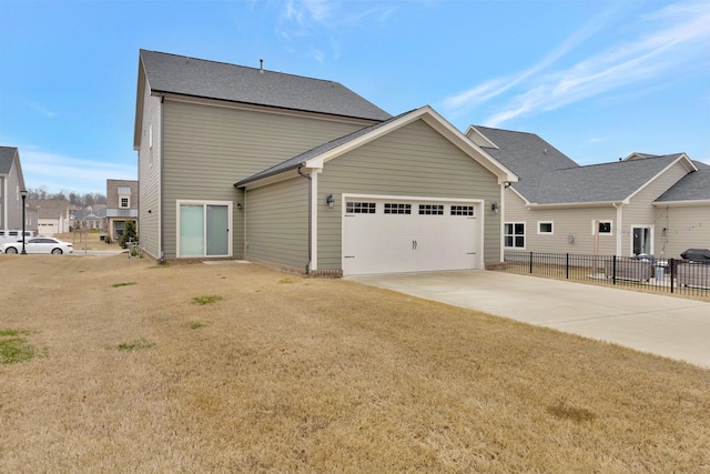 view of side of property with a lawn, an attached garage, concrete driveway, and fence