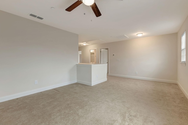 spare room featuring a ceiling fan, visible vents, baseboards, attic access, and light carpet