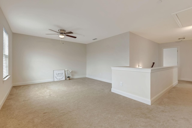 unfurnished room featuring a ceiling fan, baseboards, visible vents, attic access, and light carpet