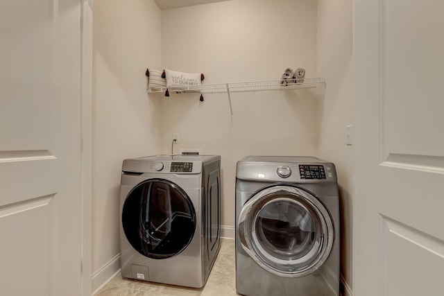 laundry room with light tile patterned floors, laundry area, washing machine and dryer, and baseboards