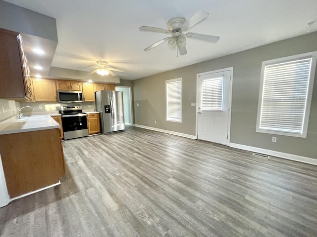 kitchen featuring baseboards, light countertops, appliances with stainless steel finishes, wood finished floors, and a ceiling fan