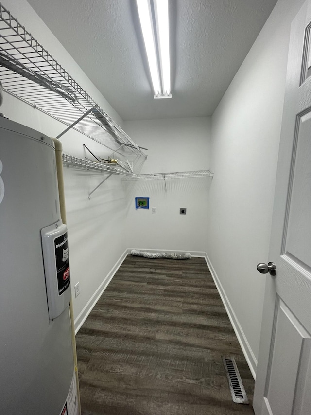 washroom featuring visible vents, electric water heater, laundry area, dark wood-style floors, and a textured ceiling