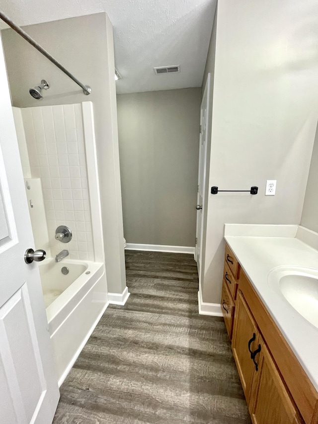 bathroom featuring visible vents, baseboards, bathing tub / shower combination, wood finished floors, and a textured ceiling