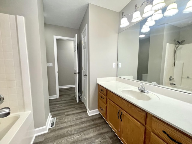 full bath with visible vents, baseboards, shower / tub combination, wood finished floors, and vanity