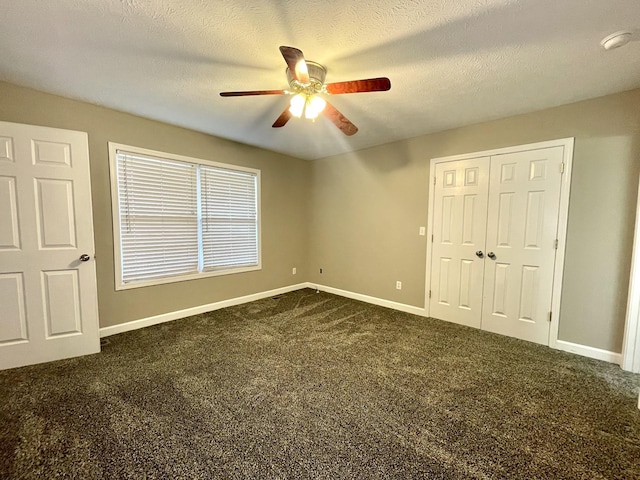 unfurnished bedroom with baseboards, a textured ceiling, and dark carpet