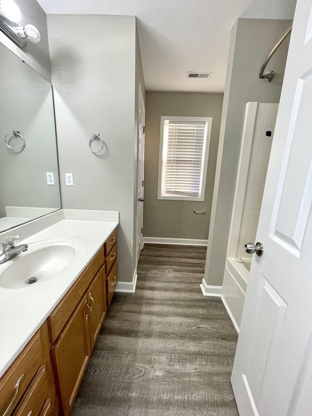 full bath featuring visible vents, baseboards, wood finished floors, and vanity