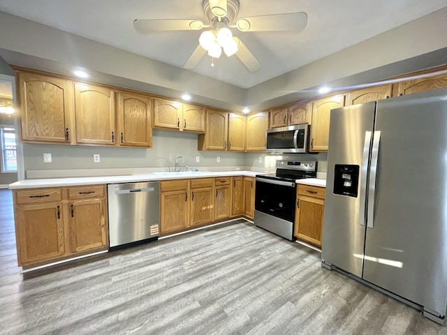 kitchen with a ceiling fan, a sink, light countertops, light wood-style floors, and appliances with stainless steel finishes