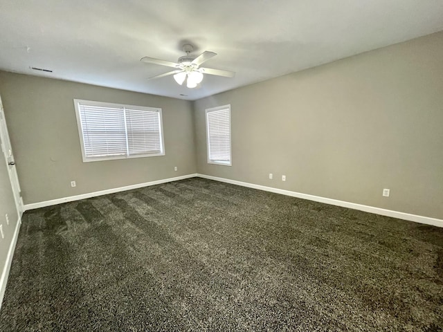 spare room featuring a ceiling fan, baseboards, and dark colored carpet