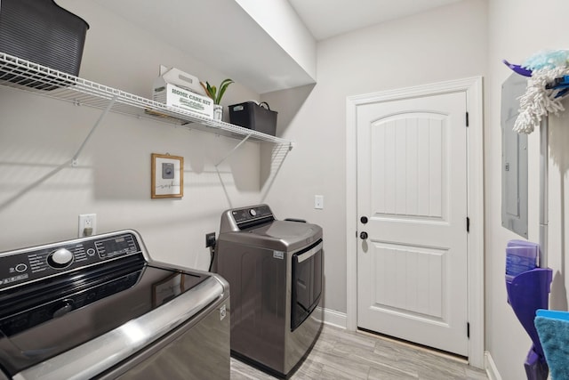 laundry area with laundry area, washer and dryer, light wood-style flooring, and baseboards