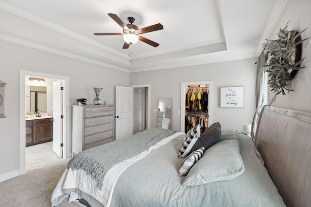 bedroom with a tray ceiling, ornamental molding, a spacious closet, a closet, and light colored carpet