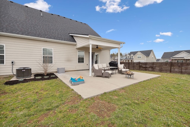 back of property with a patio, cooling unit, a ceiling fan, an outdoor living space with a fire pit, and a lawn