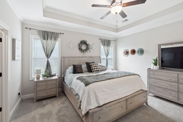 carpeted bedroom with visible vents, a ceiling fan, a tray ceiling, crown molding, and baseboards