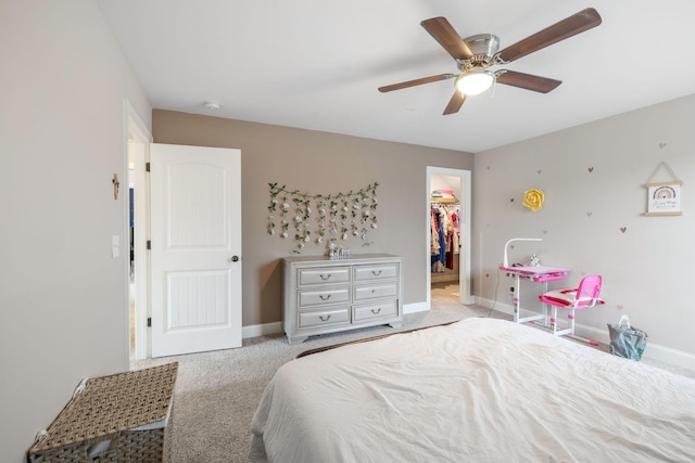 carpeted bedroom featuring a spacious closet, ceiling fan, a closet, and baseboards