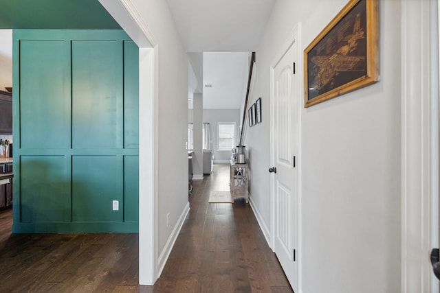 hallway featuring dark wood finished floors and baseboards