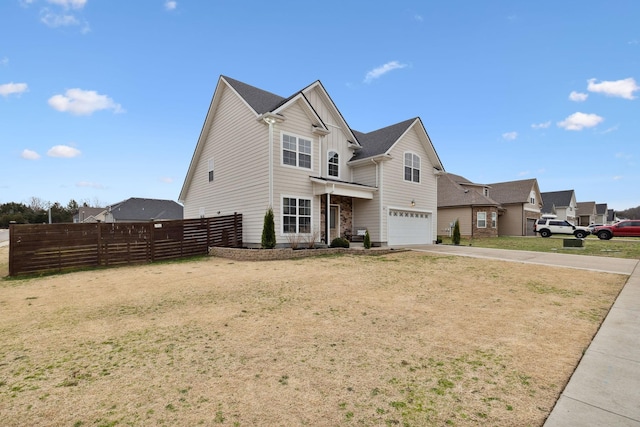 traditional home featuring a front yard, fence, a garage, and driveway