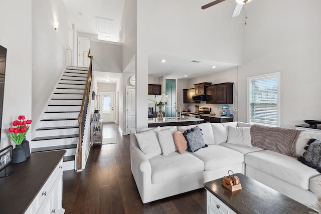 living area with stairs, recessed lighting, a high ceiling, dark wood-style floors, and a ceiling fan