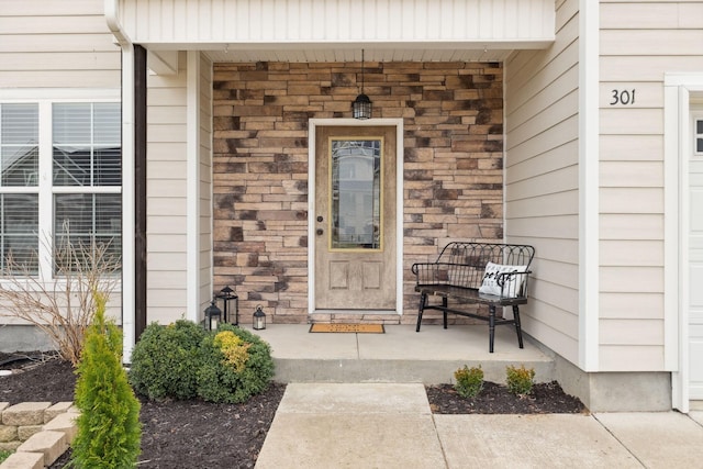 doorway to property featuring a porch and stone siding