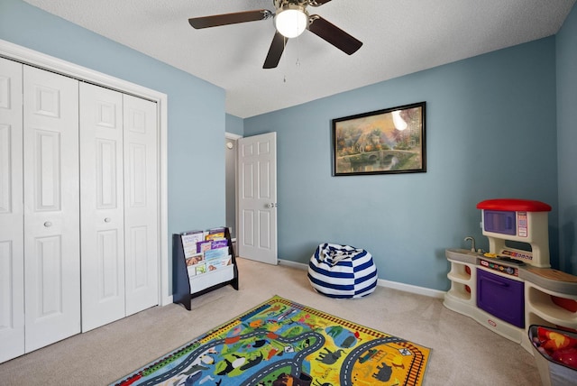 recreation room with baseboards, a textured ceiling, ceiling fan, and carpet flooring