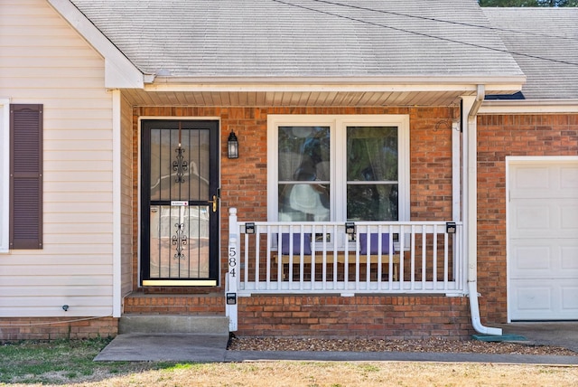 entrance to property with a garage, brick siding, covered porch, and a shingled roof