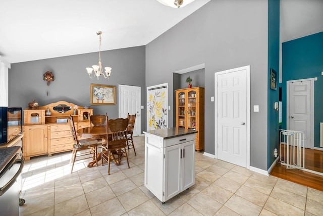 kitchen with light tile patterned floors, dark countertops, a chandelier, and white cabinetry