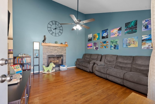 living room with a fireplace, baseboards, ceiling fan, and wood finished floors