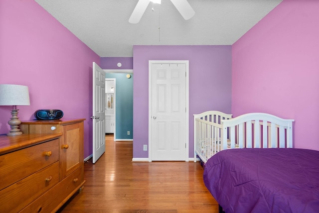 bedroom featuring ceiling fan, baseboards, a textured ceiling, and wood finished floors