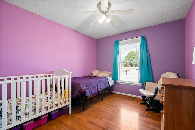 bedroom with baseboards, visible vents, wood-type flooring, and a textured ceiling