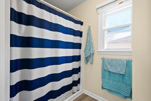 full bathroom with a shower with shower curtain, baseboards, and wood finished floors