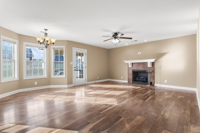 unfurnished living room featuring visible vents, baseboards, a tile fireplace, wood-type flooring, and ceiling fan with notable chandelier