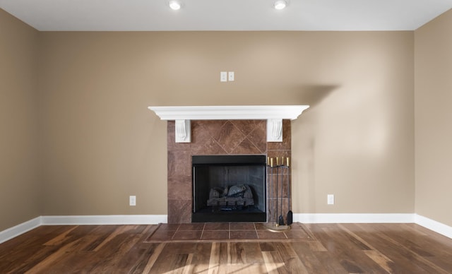 room details featuring baseboards, wood finished floors, and a tiled fireplace