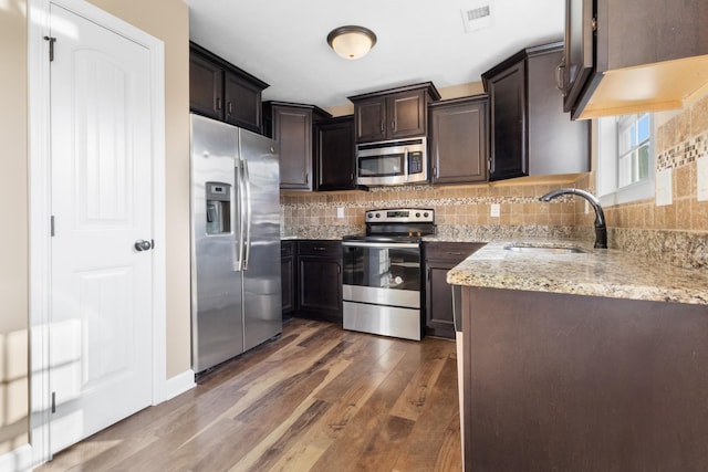 kitchen with tasteful backsplash, visible vents, light stone countertops, appliances with stainless steel finishes, and a sink